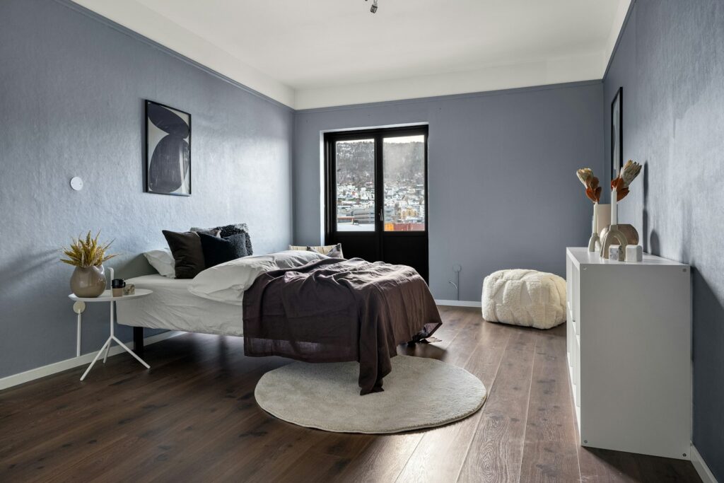A bedroom with blue walls and hardwood floors