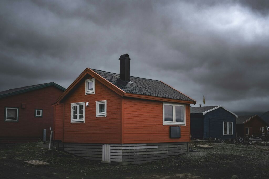a red house sitting on top of a dirt field