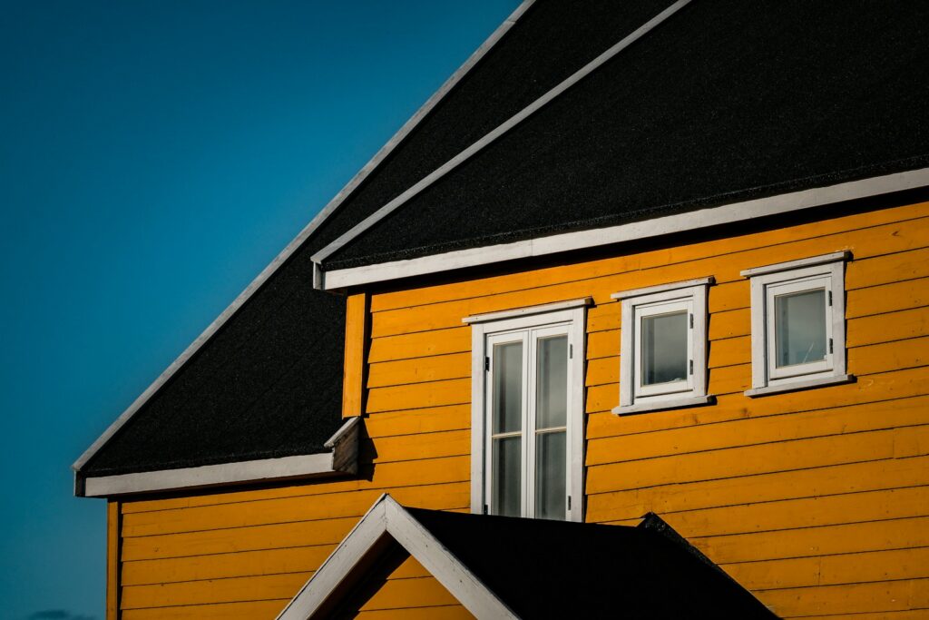 Yellow house with black roof against blue sky.