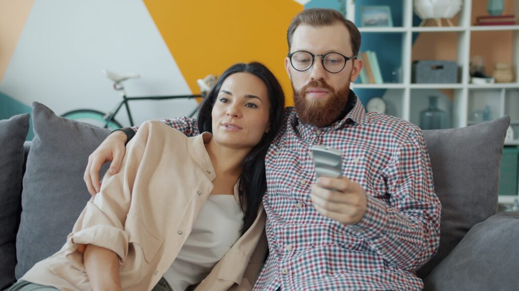 Couple sitting on couch, man holding credit card.