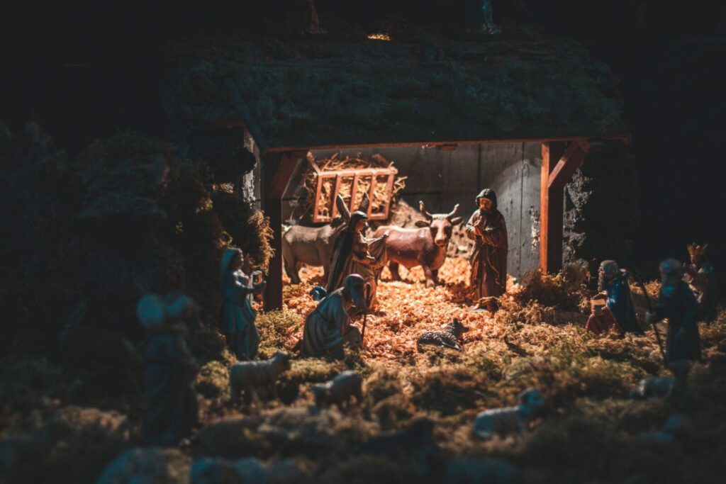 A beautifully illuminated Christmas nativity scene featuring figurines of Mary, Joseph, Jesus, and animals in a stable setting.