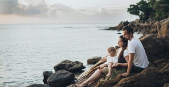 A serene family moment by the seaside, capturing love and relaxation at sunset.