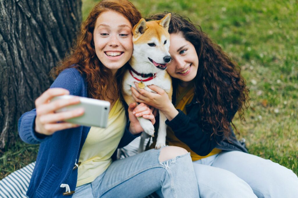 two women sitting next to each other holding a dog