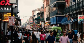 Bustling street scene in the New Orleans French Quarter filled with tourists and local shops.