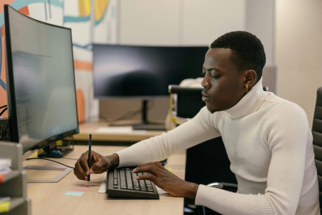 A professional adult working on a computer in an office setting, showcasing concentration and modern technology.