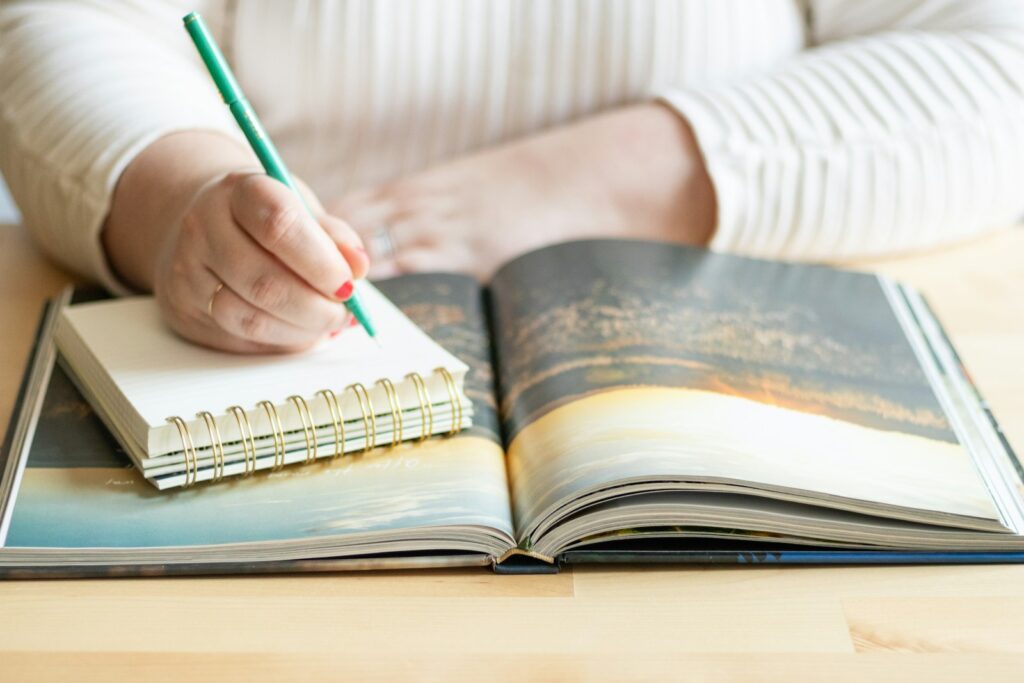 a person writing on a book with a pen