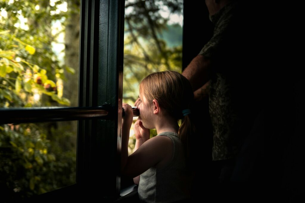 Girl looking through binoculars out window