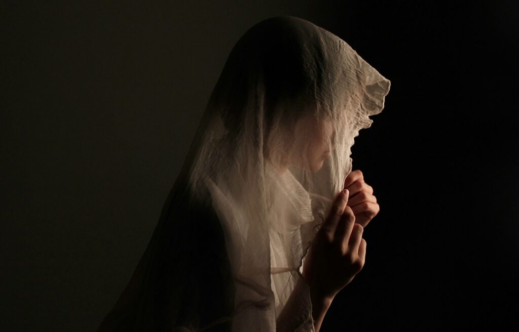 A woman in a veil holding her hands to her face