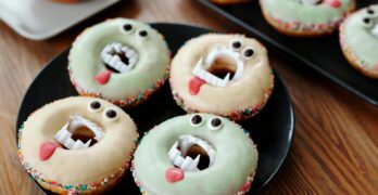 Colorful monster-themed donuts with spooky eyes and teeth, perfect for Halloween festivities.