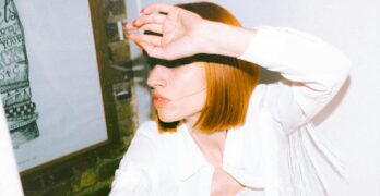 Stylish redhead woman in white outfit posing indoors in Montréal, QC, Canada.