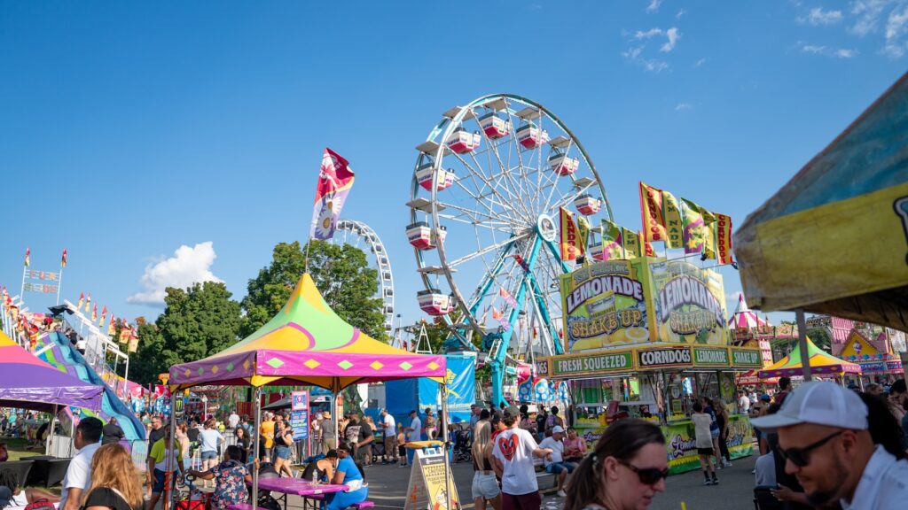 A carnival filled with lots of people next to a ferris wheel