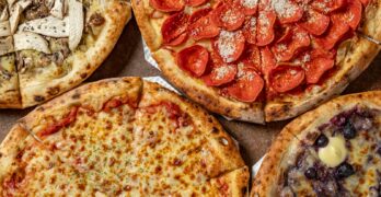 a variety of pizzas sitting on top of a table