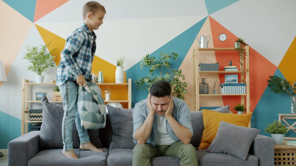 Father stressed as son jumps on couch