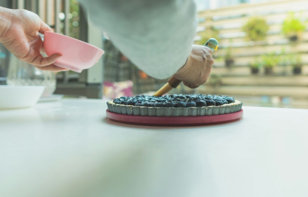person preparing a blueberry cheesecake