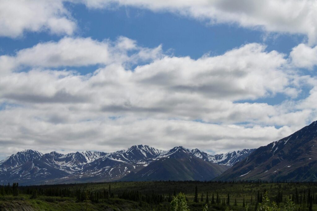 Breathtaking scenic view of snow-capped mountains in Healy, Alaska with cloudy sky.