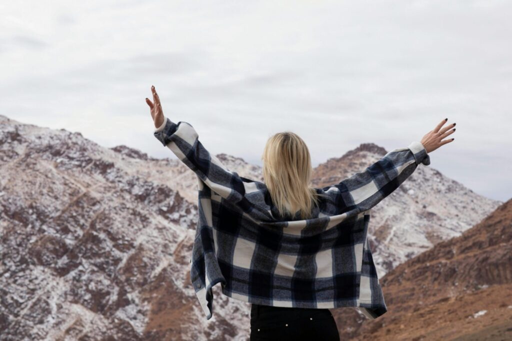 A woman with arms raised in a snowy mountain setting, enjoying a sense of freedom and adventure.