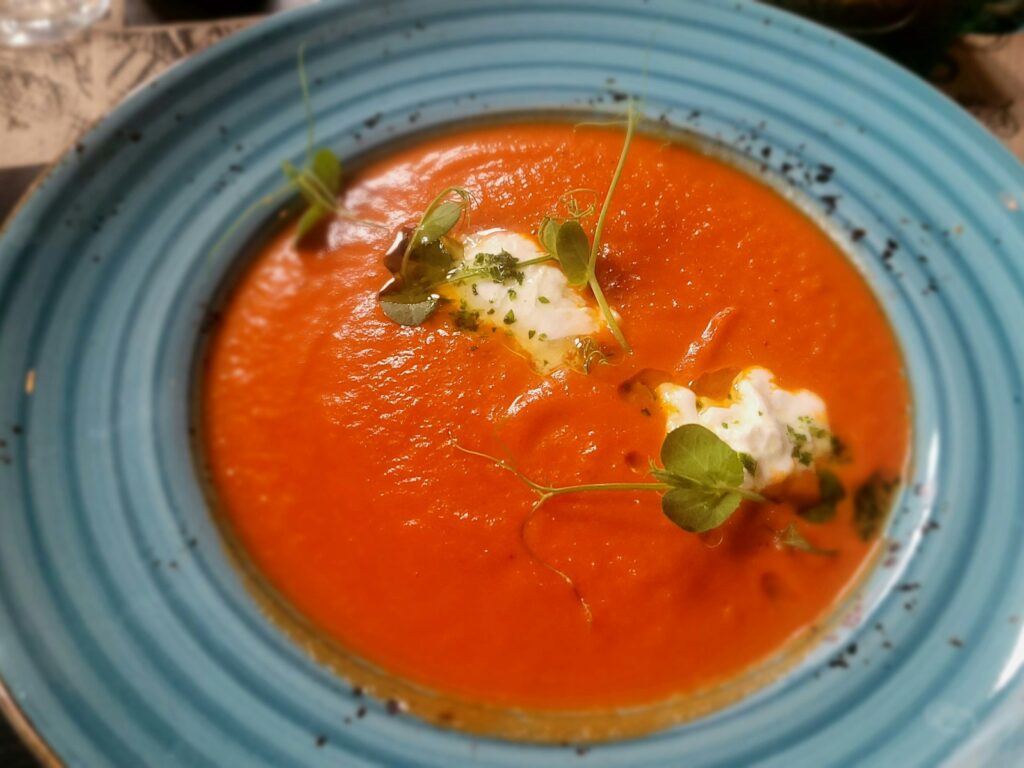 Tomato soup with a swirl of cream and greens.