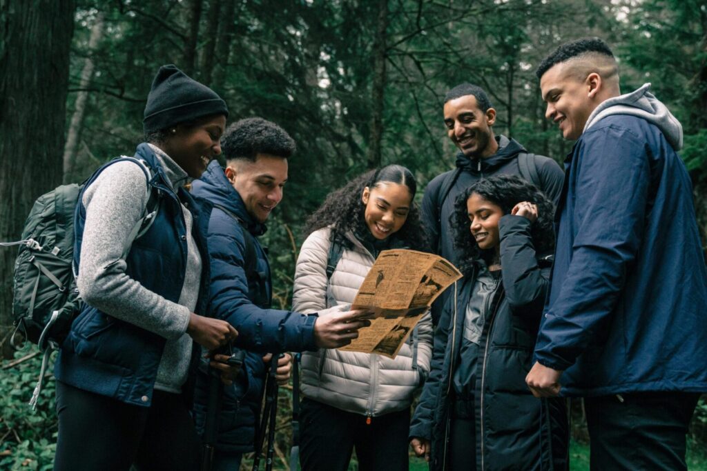Diverse group of friends hiking together, planning their adventure in a lush forest.