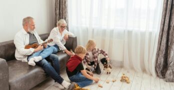 Grandparents enjoy music while children play with toys in a cozy living room.