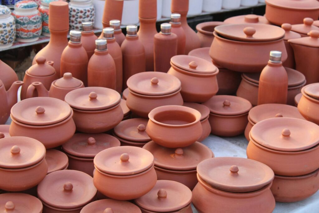 A variety of handmade clay pots and vases displayed on a market table.