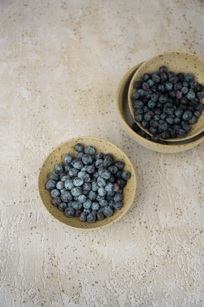 two bowls of blueberries on a table