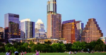 people sitting on green grass field near city buildings during daytime