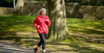 Elderly woman enjoying a healthy outdoor jog in a sunlit park.