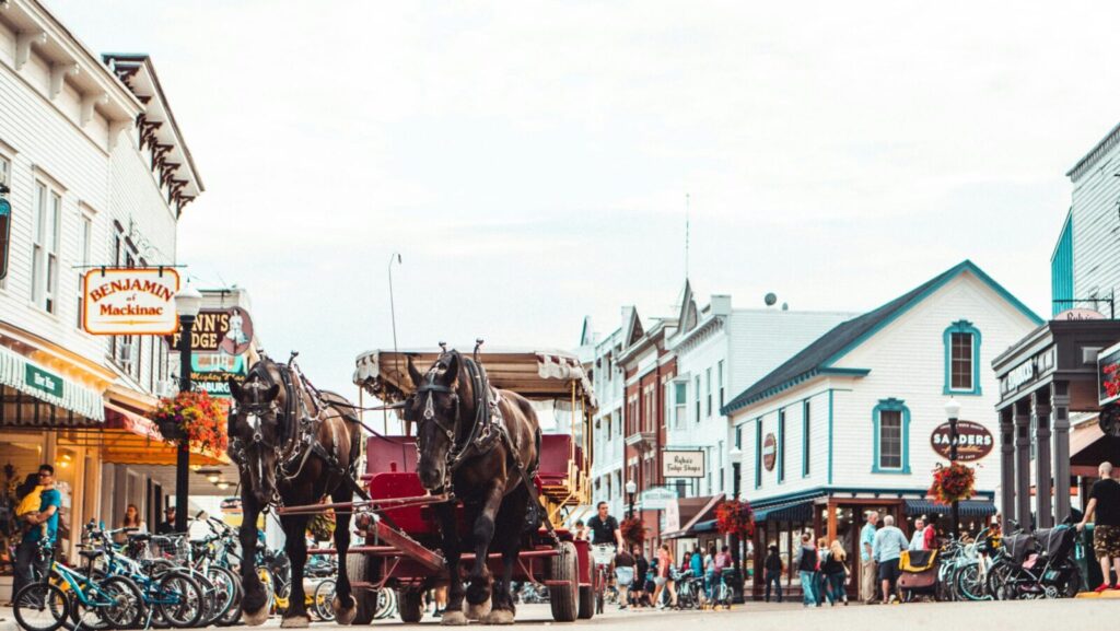 A bustling Mackinac Island street scene featuring a horse-drawn carriage and vibrant architecture.