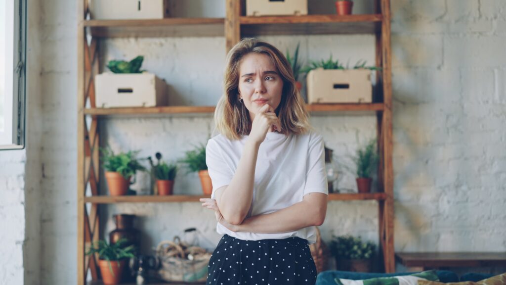 A young woman with hand on chin looking thoughtful.