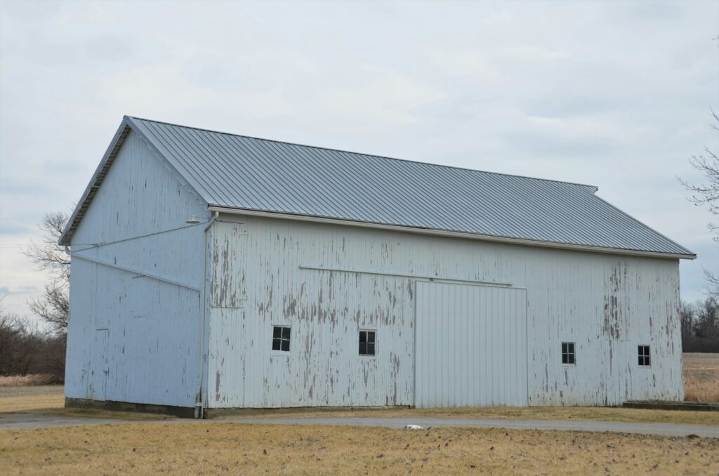 an old white barn with a metal roof
