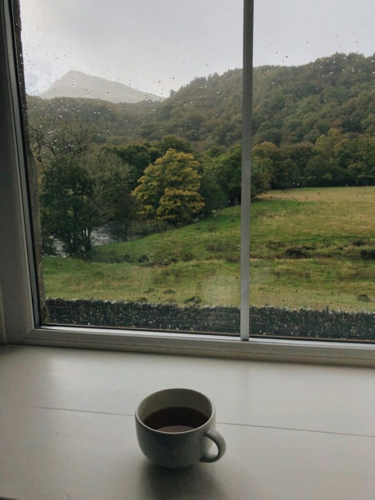 Cozy window view of Welsh hills and a cup of coffee on a rainy day.