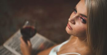 a woman holding a glass of wine and reading a book