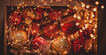 A box of vibrant Christmas ornaments wrapped in warm twinkling lights, perfect for holiday celebrations.