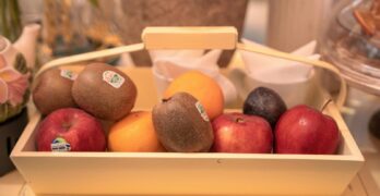 A charming arrangement of fruits including apples, kiwis, and oranges in a wooden basket.