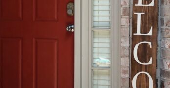 a welcome sign sitting in front of a red door