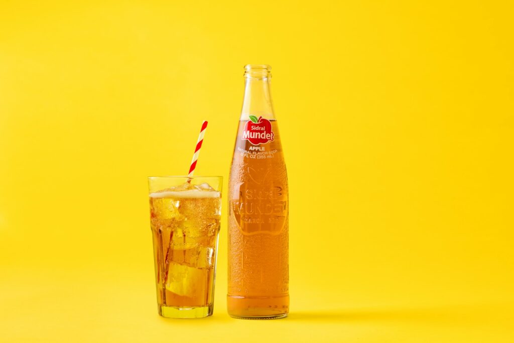 A bottle of soda and a drink with ice.