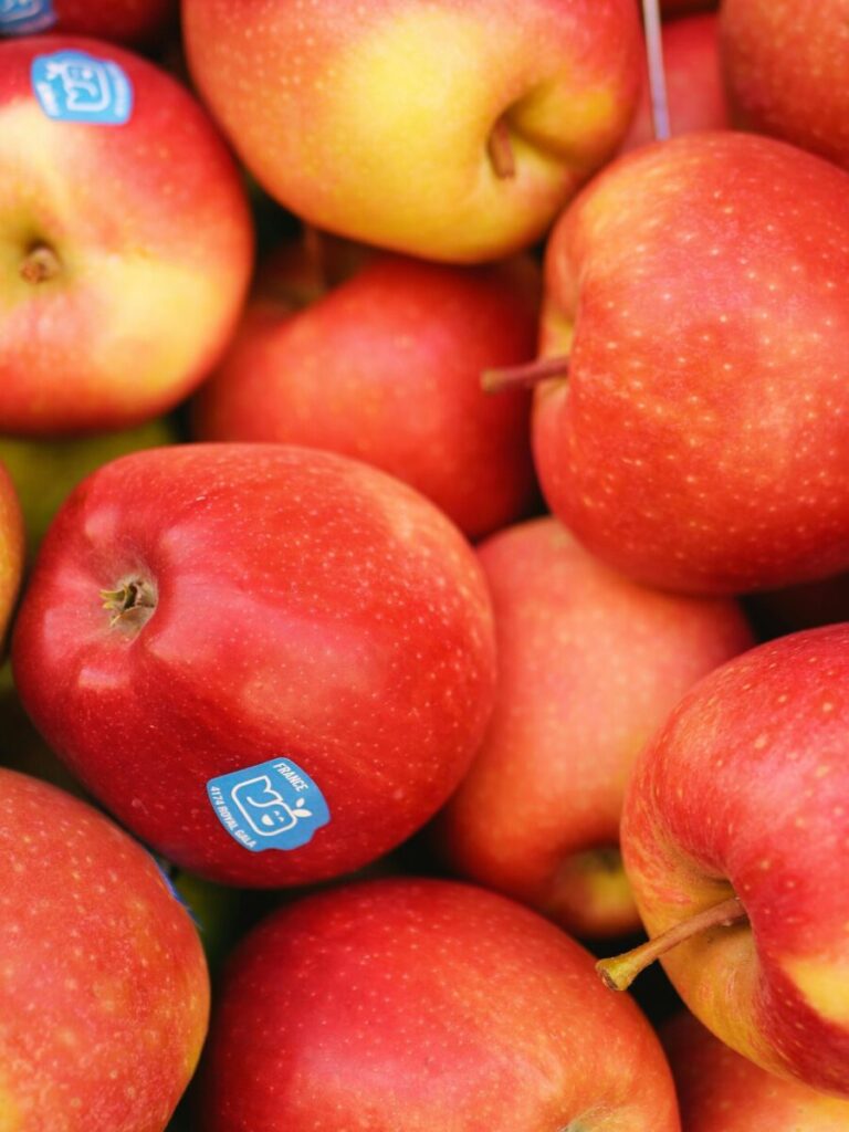 Close-up of fresh red apples with stickers in a grocery store display, showcasing vibrant colors.