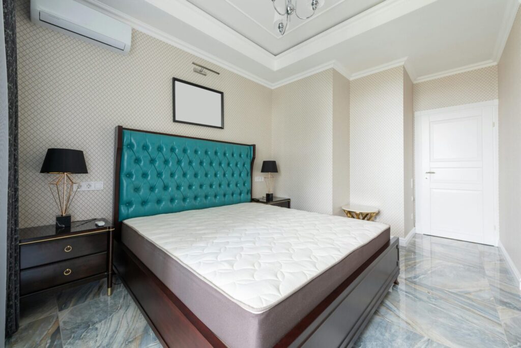 Stylishly designed modern bedroom with luxurious teal headboard and marble floor.