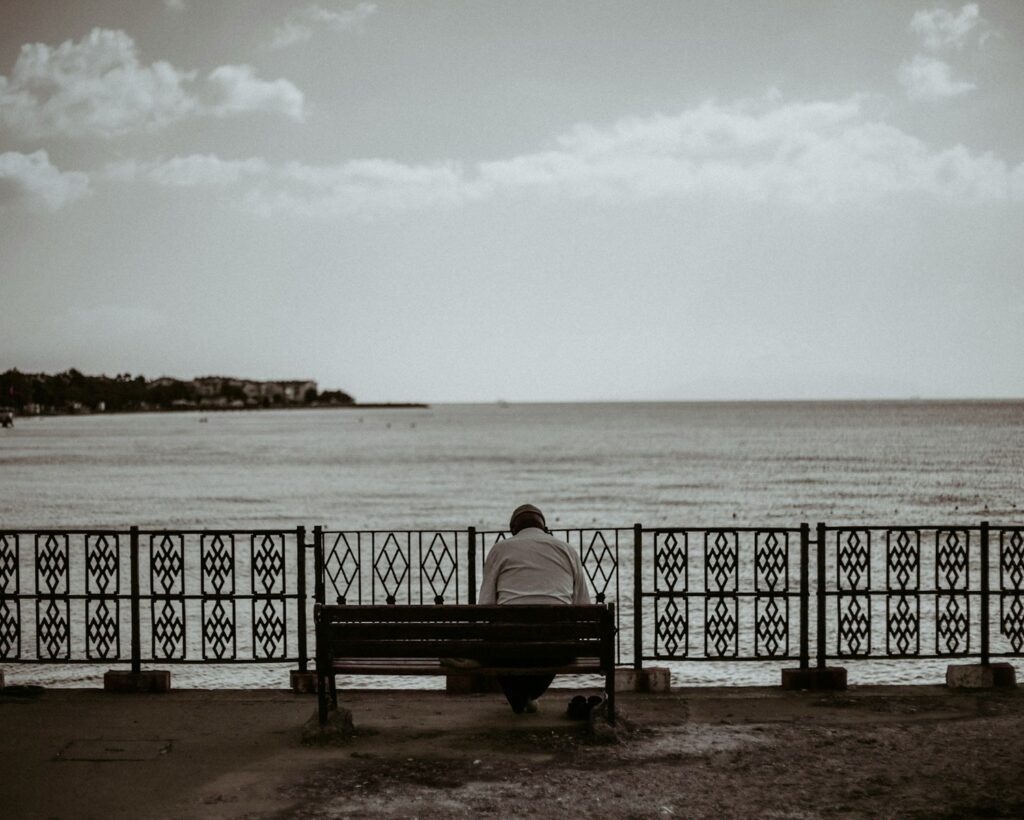 woman sitting on bench near sea during daytime