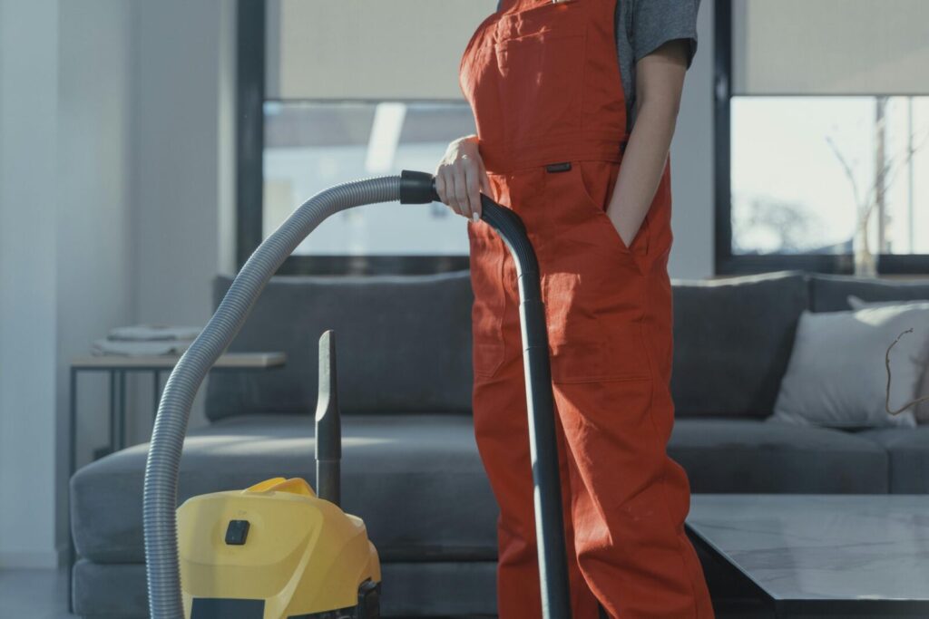 Cleaner using a vacuum in a stylish indoor setting, showcasing cleaning equipment and techniques.