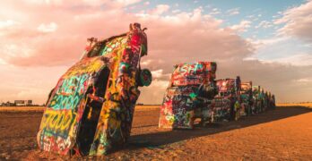 Colorful graffiti on cars at Cadillac Ranch in Amarillo, Texas at sunset.