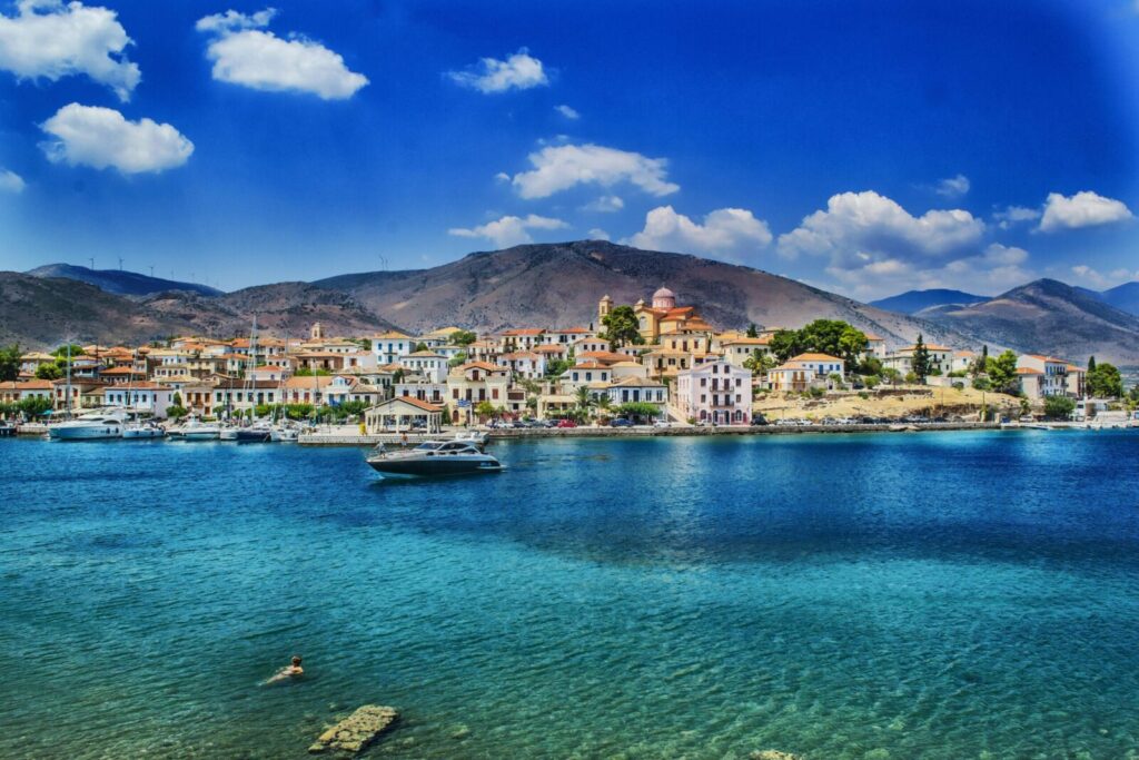 Beautiful coastal view of a charming Greek town against a mountainous backdrop, ideal for travel and vacation imagery.
