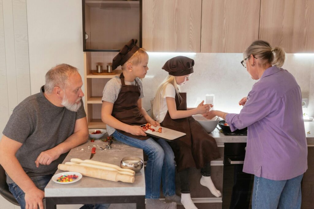 Grandparents cooking with grandchildren in a warm family setting.
