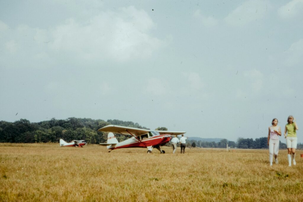 white and red plane on green grass field under white clouds during daytime
