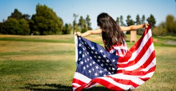 girl holding US flag on grassland
