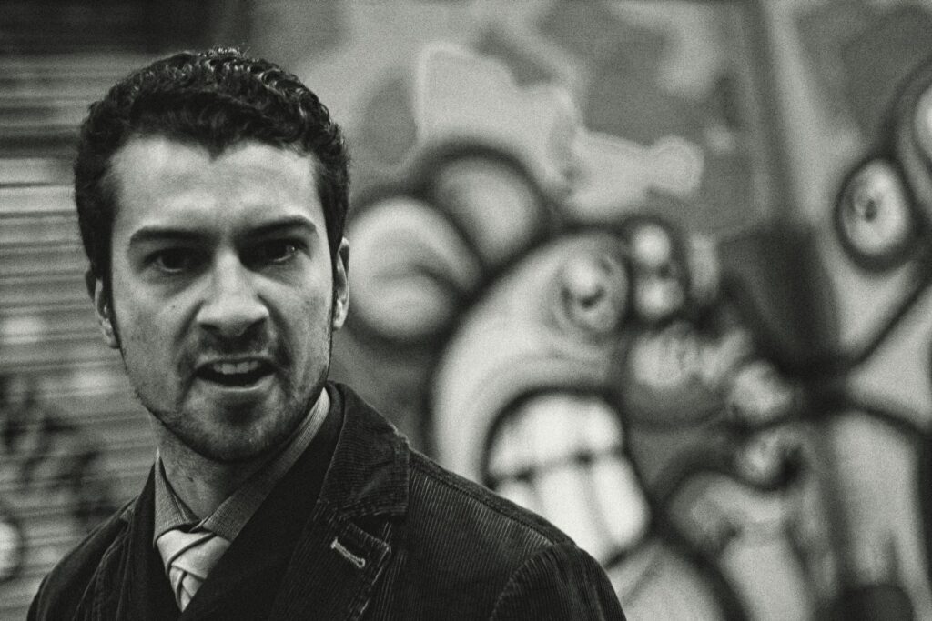 a black and white photo of a man in front of a graffiti wall
