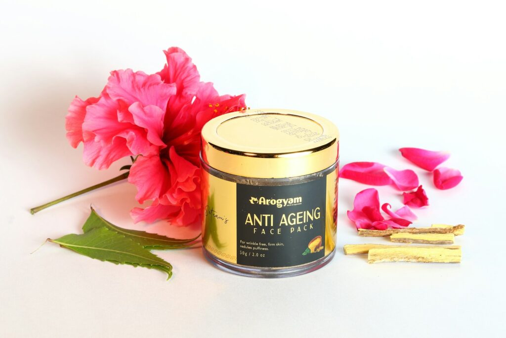 a pink flower next to a tin of anti - aging face mask