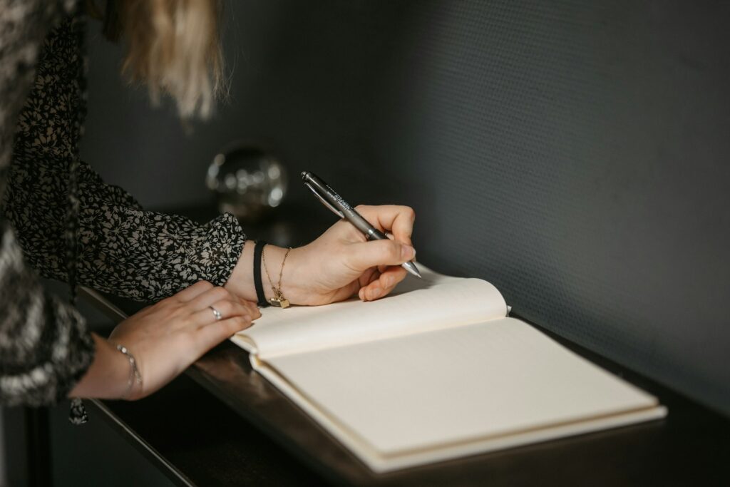 a woman writing on a notebook with a pen