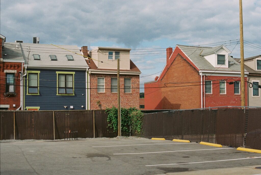 A parking lot with a fence in front of a row of houses