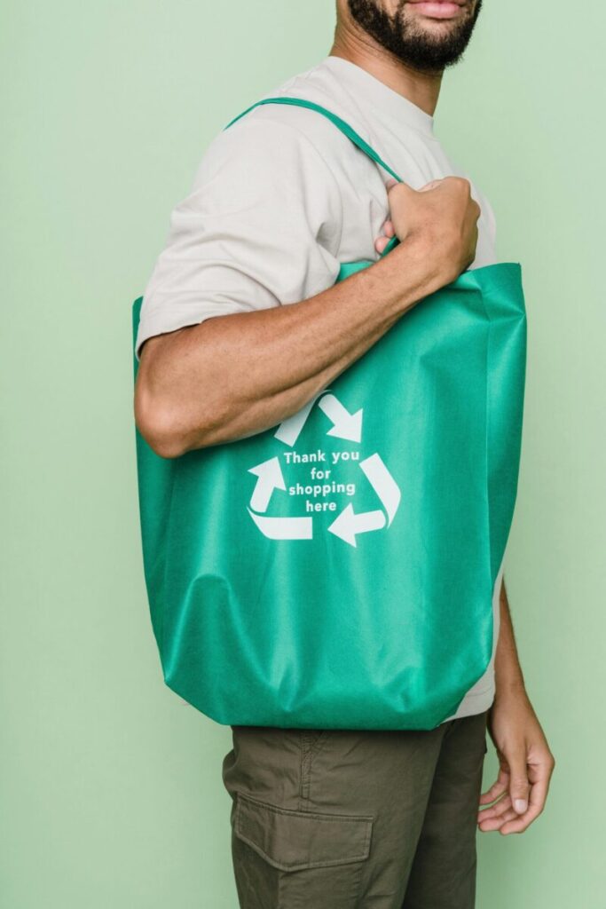 Man holding a green recycle bag in studio, promoting sustainability.